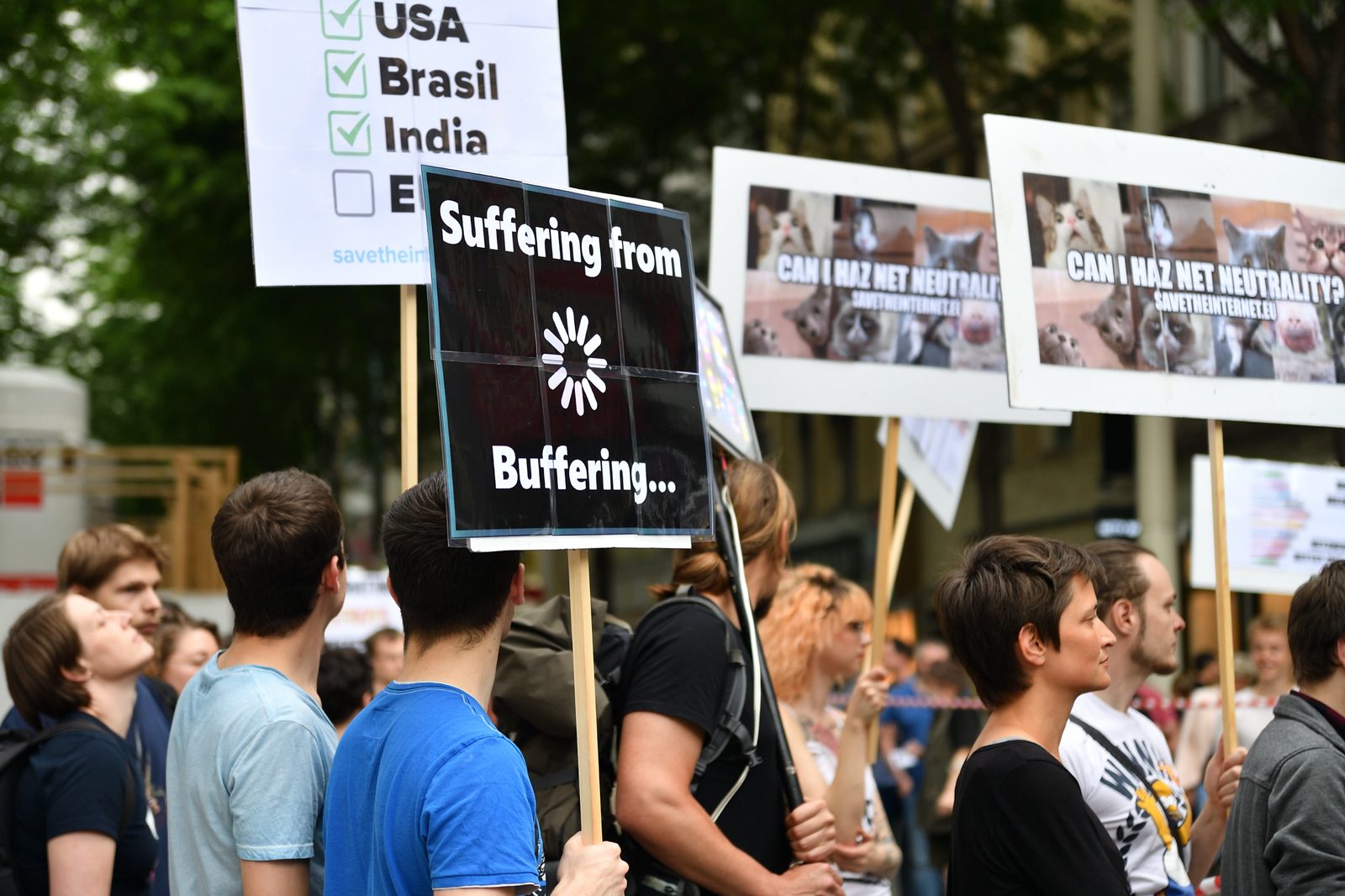 Protester holding a &ldquo;Suffering from Buffering&rdquo; sign next to a &ldquo;Who has net neutrality&rdquo; checklist at the 2016 Vienna protest
