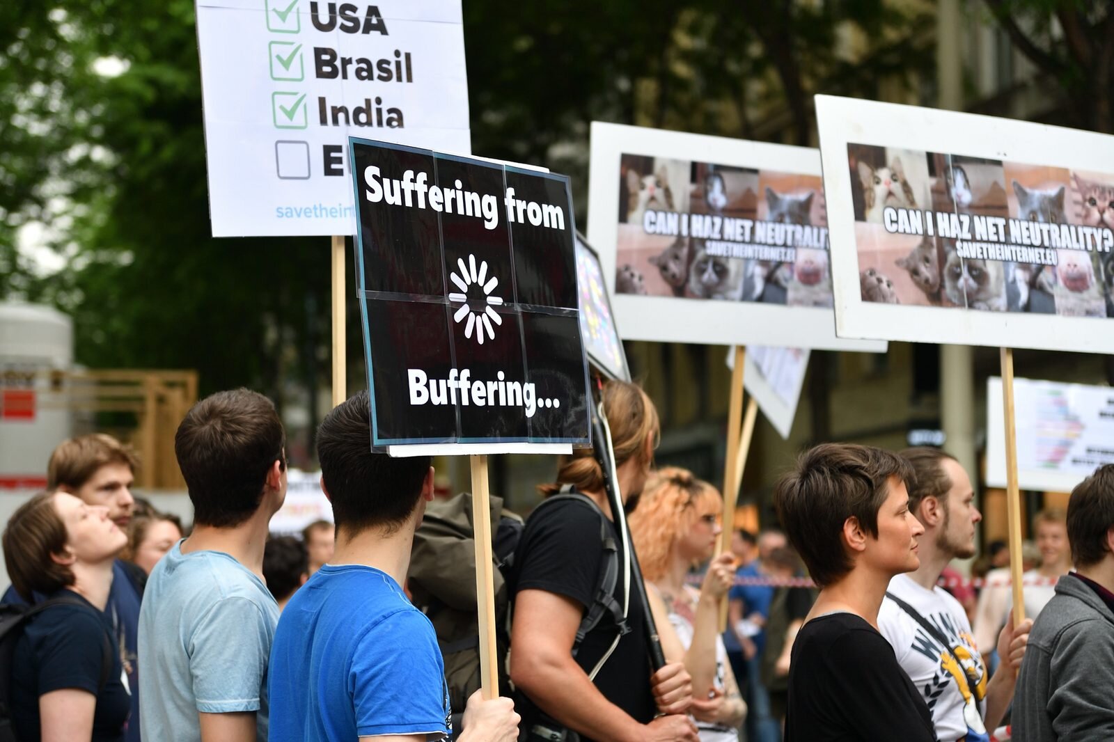 Protester holding a “Suffering from Buffering” sign next to a “Who has net neutrality” checklist at the 2016 Vienna protest